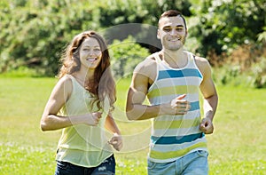Couple of joggers doing running at park and smiling