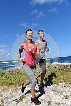 Couple of joggers running on the coastline photo
