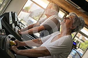 Couple on jogging machine. Senior couple workout in the g