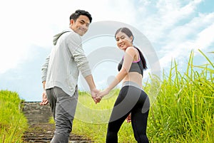 Couple jogging up stair in forest, holding hands together