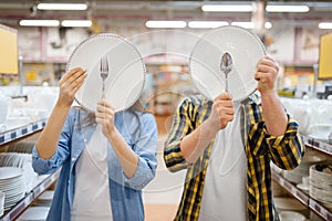 Couple jokes with plates in houseware store