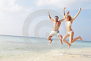 Couple Jumping In The Air On Tropical Beach