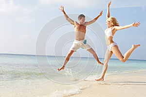 Couple Jumping In The Air On Tropical Beach