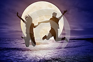 Couple jumping on beach and watching the moon.Celebrate Mid autumn festival