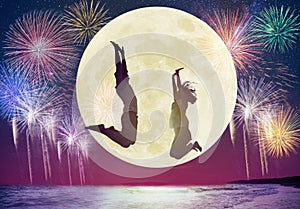 couple jumping on beach and watching the moon.Celebrate Mid autumn festival concepts