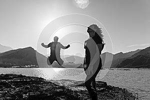 Couple jumping and enjoying a natural landscape of mountains and lake.