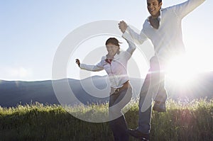 Couple Jumping While Holding Hands In Park