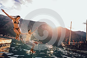 Couple jumping from a pier into the water