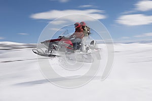 Couple Jumping Snowmobile In Snow