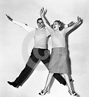 Couple jumping with their arms outstretched