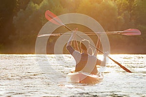 Couple kayaking on river with sunset on background