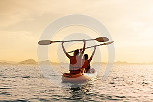 Couple kayaking together. Beautiful young couple kayaking on lake together and smiling at sunset