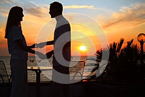 Couple keep for hands against sunset on sea