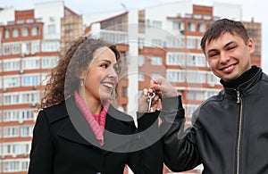 Couple with key against many-storeyed house