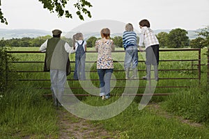 Couple With Kids Looking At Lush Landscape By Fence