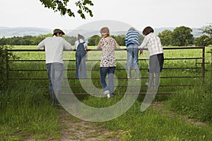 Couple With Kids Looking At Lush Landscape By Fence