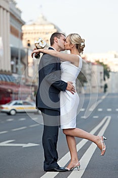 Couple in a kiss on the road. Newlyweds kissing on the dividing strip. Wedding theme.