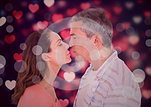 Couple kissing against digitally generated background with hearts