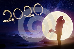 couple kissing on beach and watching the moon.Celebrate new year 2020 concept