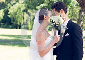 Couple kissing behind bouquet in garden