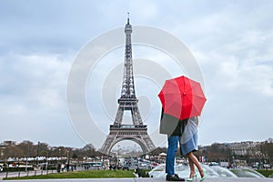 Couple kissing behind red umbrella in Paris