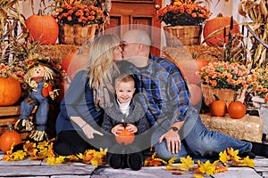 Couple kissing with child in front of them at fall