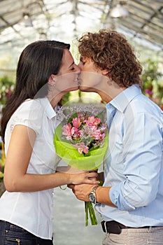 Couple kissing in flower nursery