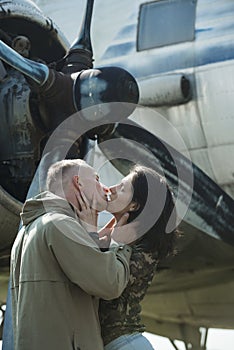 Couple kissing in front of propeller of old plane on sunny day. Couple in love full of desire hugs near airplane on