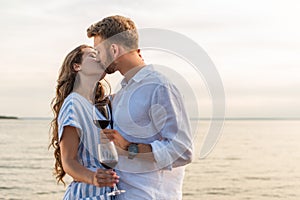 Couple kissing and holding glasses with