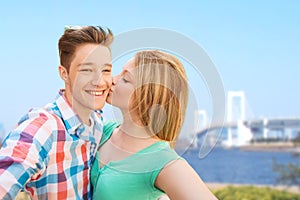 Couple kissing and taking selfie over bridge
