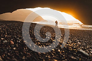 Couple kissing under arch on Legzira ocean beach and enjoying fantastic sunset