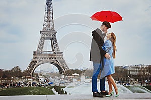 couple kissing under umbrella near Eiffel Tower, honeymoon in Paris