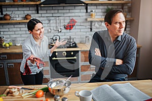 Couple in kitchen. Theey have argue. Guy doesn`t listen to woman. She try to talk to him. They are upset and unhappy.