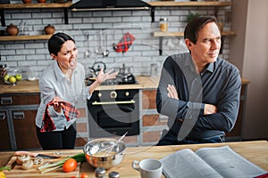 Couple in kitchen. Theey have argue. Guy doesn`t listen to woman. She try to talk to him. They are upset and unhappy. photo