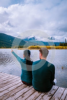Couple by the lake watching sunset, Pyramid lake Jasper during autumn in Alberta Canada, fall colors by the lake during