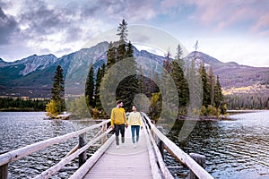 Couple by the lake watching sunset, Pyramid lake Jasper during autumn in Alberta Canada, fall colors by the lake during