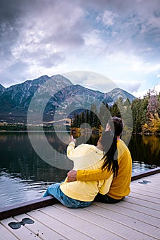 Couple by the lake watching sunset, Pyramid lake Jasper during autumn in Alberta Canada, fall colors by the lake during