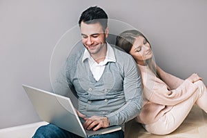 Couple with laptop, sitting on floor