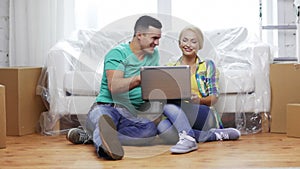 Couple with laptop sitting on floor in new house