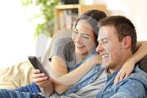 Couple laughing watching media content in a phone
