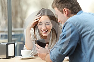 Couple laughing watching media in smart phone