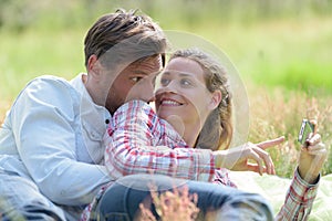 couple lay on grass and hold smart-phone