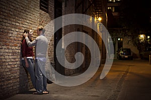 Couple leaning against brick wall in alley way