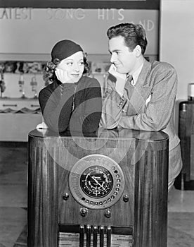 Couple leaning on a radio and looking at each other