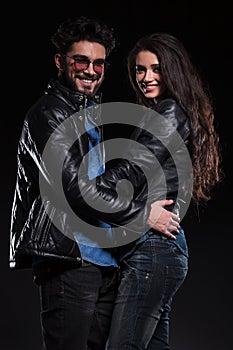 Couple in leather jacket standing embraced and smile