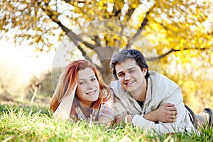 Couple lie at green grass in the park.