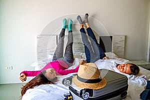 Couple lies on the bed with suitcase. Fees on journey concept. Luggage preparation.