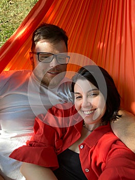 a couple lies in a hammock overlooking a house in a village