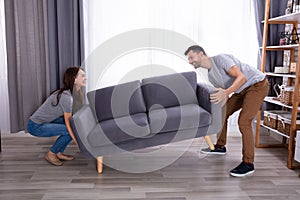 Couple lifting sofa in living room