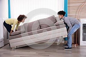 Couple Lifting Sofa In Living Room